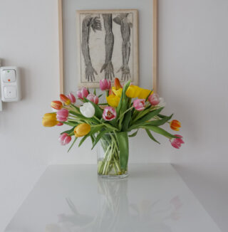 Ein Blumenstrauss auf einem schreibtisch vor einem bild mit händen