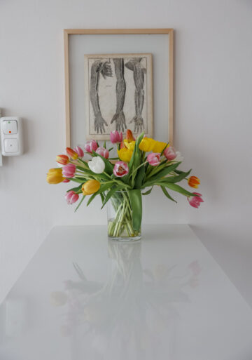 Ein Blumenstrauss auf einem schreibtisch vor einem bild mit händen