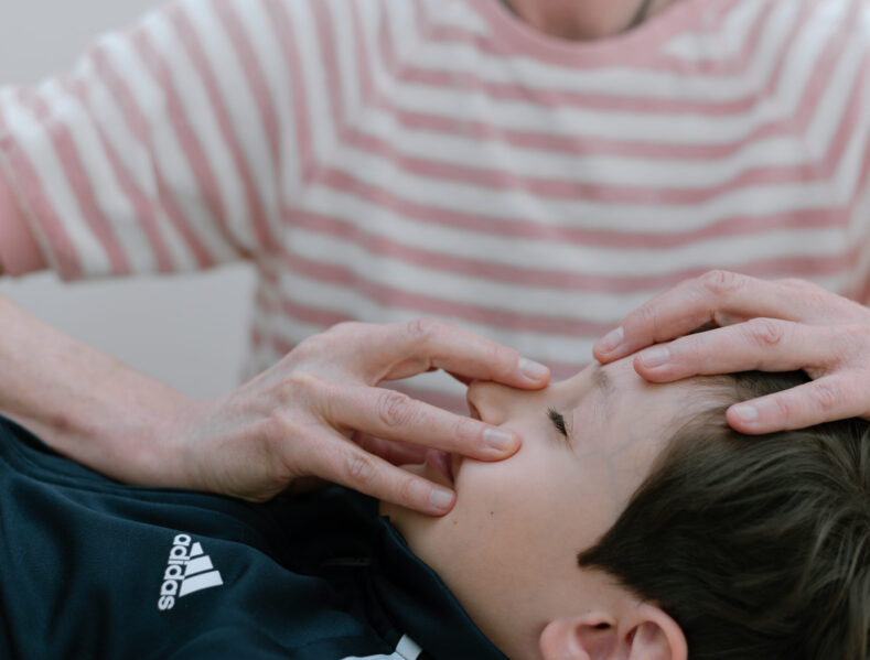 Kinderosteopathie: sanfte Behandlung am Gesicht eines Jungen – Praxis Benedikt München