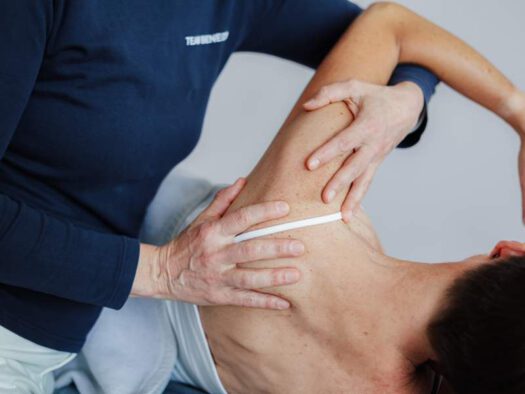 Physiotherapeutin behandelt die Schulter einer Patientin – Physiotherapie bei Schulter-Impingement in München
