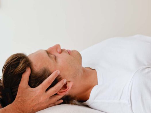 Osteopathin behandelt sanft Kopf und Ohrbereich eines Patienten – Osteopathie bei Tinnitus in München